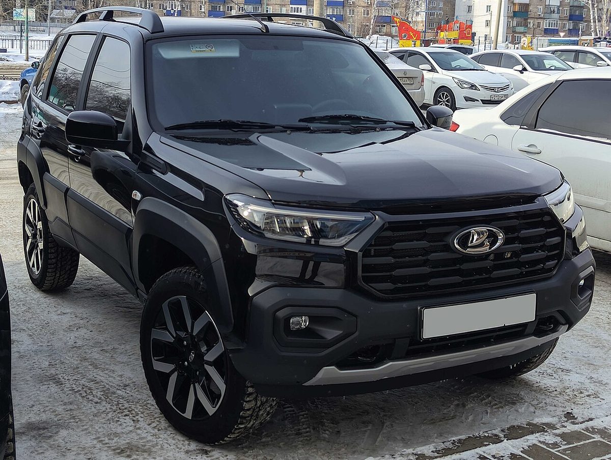 Чёрная пятидверная Lada Niva Travel 2025 года выпуска на заснеженной парковке, вид спереди сбоку