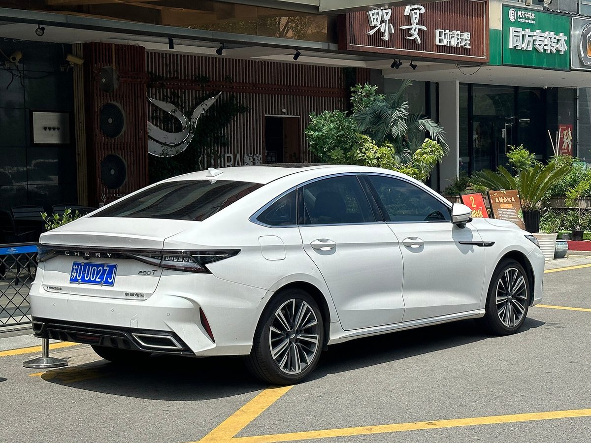 Белый Chery Arrizo 8 сзади-сбоку, виден шильдик CHERY и форма багажника