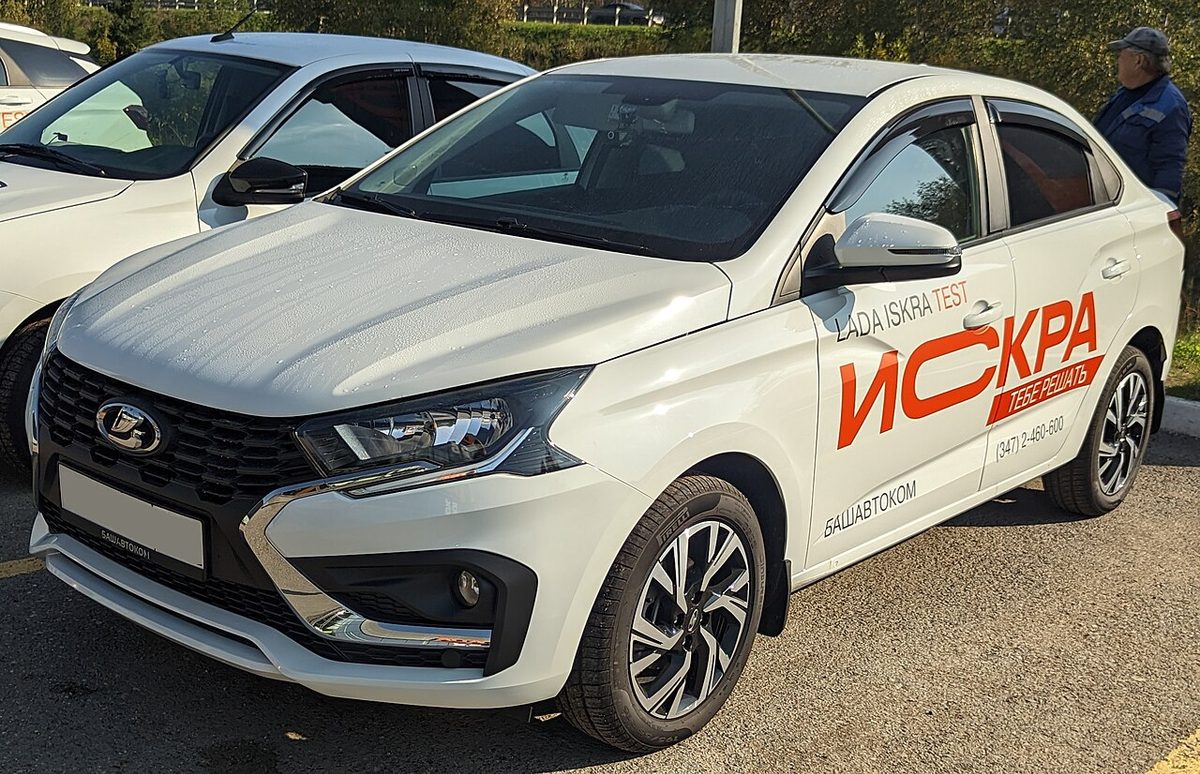 Белый седан Lada Iskra 2025 года, тестовый автомобиль дилера, вид спереди сбоку